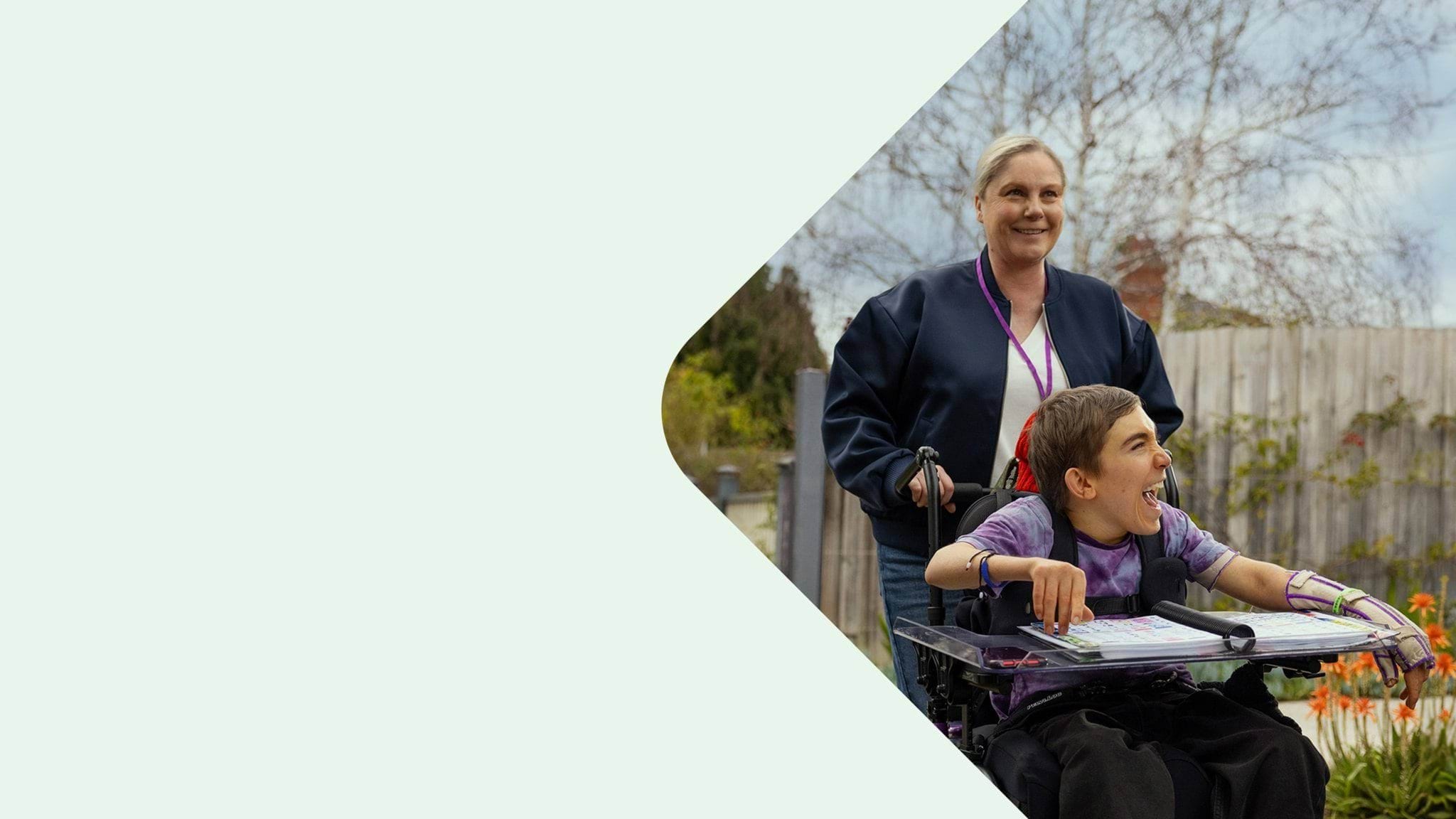 Community services carer pushing a young client in a wheelchair.